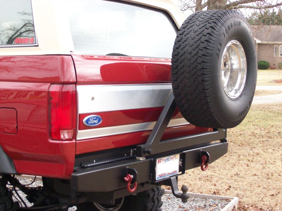 Red 1990 Ford Bronco rear bumper with mounted spare tire and tow hitch