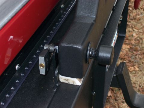 1990 Ford Bronco - A close-up view shows a red vehicle panel attached to a black metal frame, secured with a padlock.