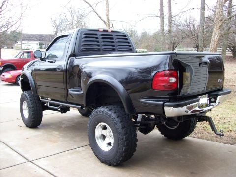 2000 Ford F-150 - Lifted black Ford F-150 pickup truck seen from the rear 3/4 angle.