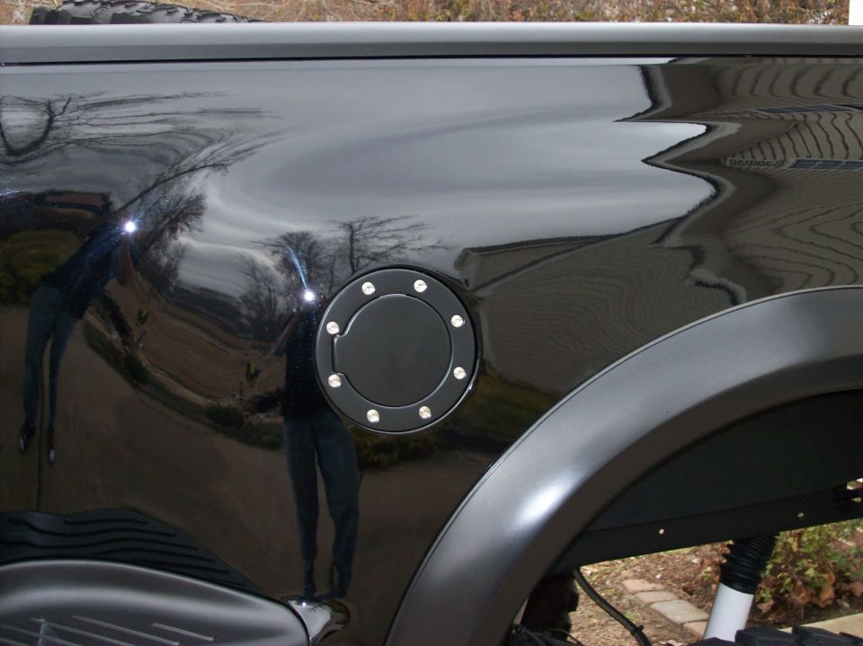 Black pickup truck fuel door with chrome accents, matte black fender flare visible