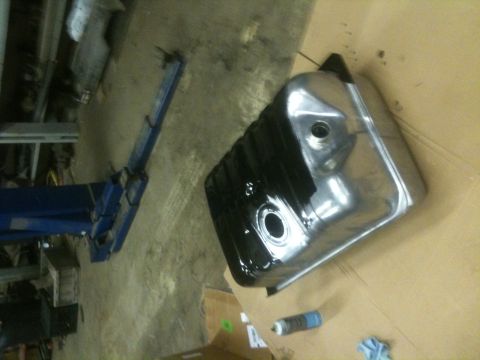 1993 Ford Bronco - A shiny fuel tank is being coated in black paint, with a spray can nearby.