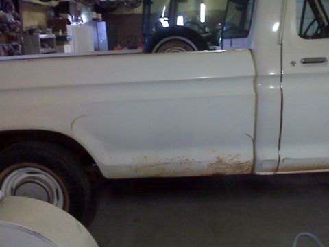 1973 Ford F-100 - 1973 Ford F-100 pickup truck side view with visible rust on the lower body panel.