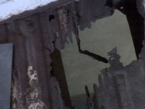 1973 Ford F-100 - The floor of a truck bed shows extensive rust damage and holes, indicating significant deterioration.