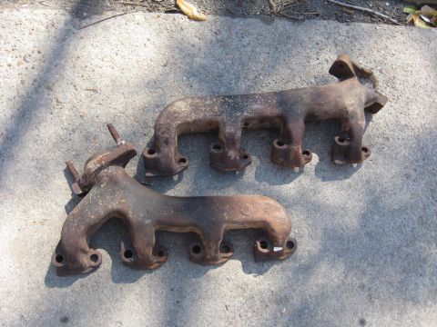 1994 Ford Bronco - Two used exhaust manifolds are shown resting on a concrete surface.