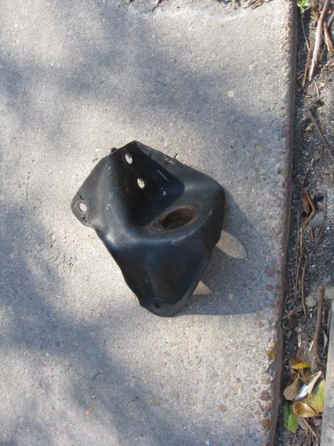1994 Ford Bronco - A black metal bracket, likely a vehicle part, rests on a concrete surface.