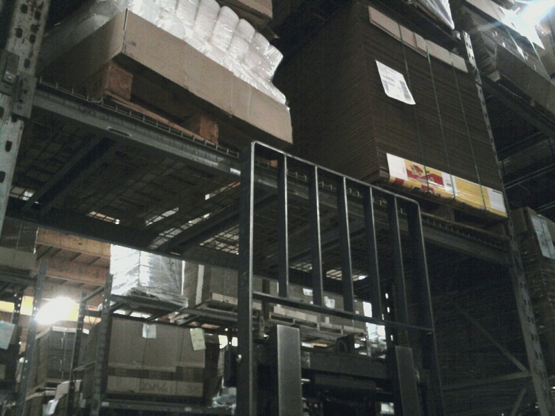 Forklift in a warehouse, near tall shelves stacked with boxes and pallets