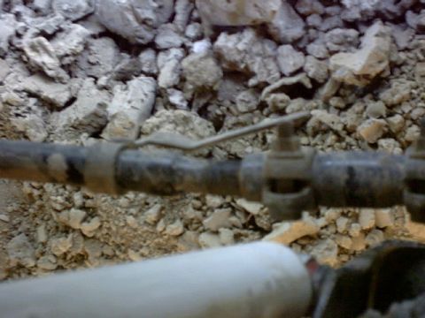 1995 Ford Bronco - A close-up view of a pipe and valve assembly, with a rocky, dirt-filled background.