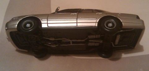 2000 Mercury Grand Marquis - Upside-down view of a silver sedan, revealing its undercarriage details. This vehicle is identified as a 2000 Mercury Grand Marquis.