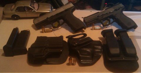 2000 Mercury Grand Marquis - A collection of firearms and accessories are displayed on a table.