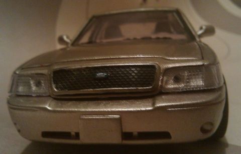2000 Mercury Grand Marquis - This is a front view of a gold toy car, resembling a 2000 Mercury Grand Marquis.