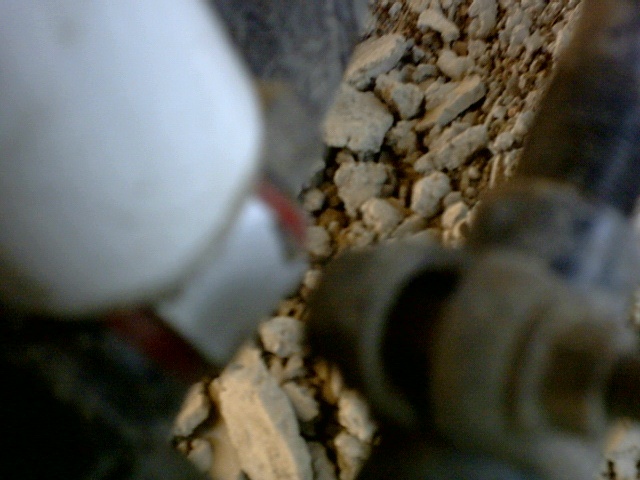 Blurry close-up of dried mud caked around vehicle undercarriage components