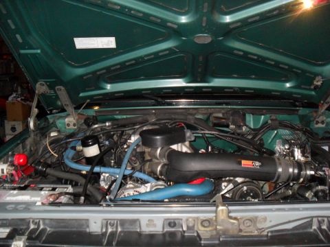 1990 Ford Bronco - The engine bay of a vehicle is shown with various hoses and components visible.