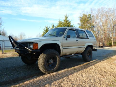1992 Ford Mustang - This tan SUV features off-road tires and a custom bull bar, viewed from the front three-quarter angle.