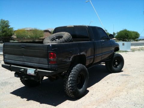 1966 Ford Bronco - Lifted black pickup truck parked outdoors under a clear blue sky.