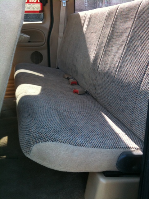 1966 Ford Bronco - The interior of a truck shows a bench seat with patterned beige upholstery and visible seatbelt latches.