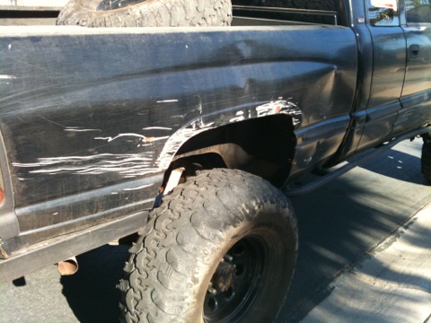 1966 Ford Bronco - This pickup truck shows extensive damage to its rear fender and body panels, with large off-road tires visible.