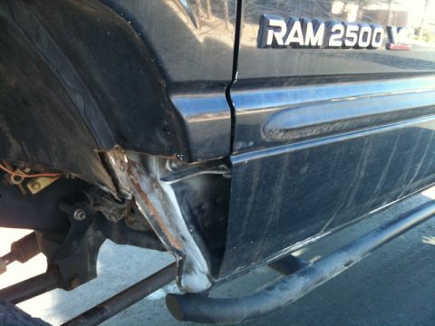 1966 Ford Bronco - The rear quarter panel of a black Dodge Ram 2500 shows significant damage and exposed metal.