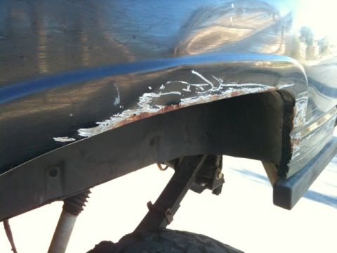 1966 Ford Bronco - The rear fender of a vehicle displays significant rust and damage, indicating wear and tear.