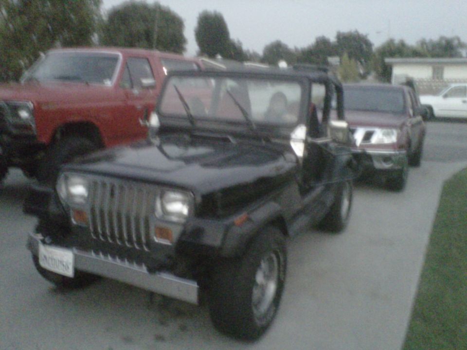 Black Jeep Wrangler with a chrome grille and bumper, parked on a concrete driveway