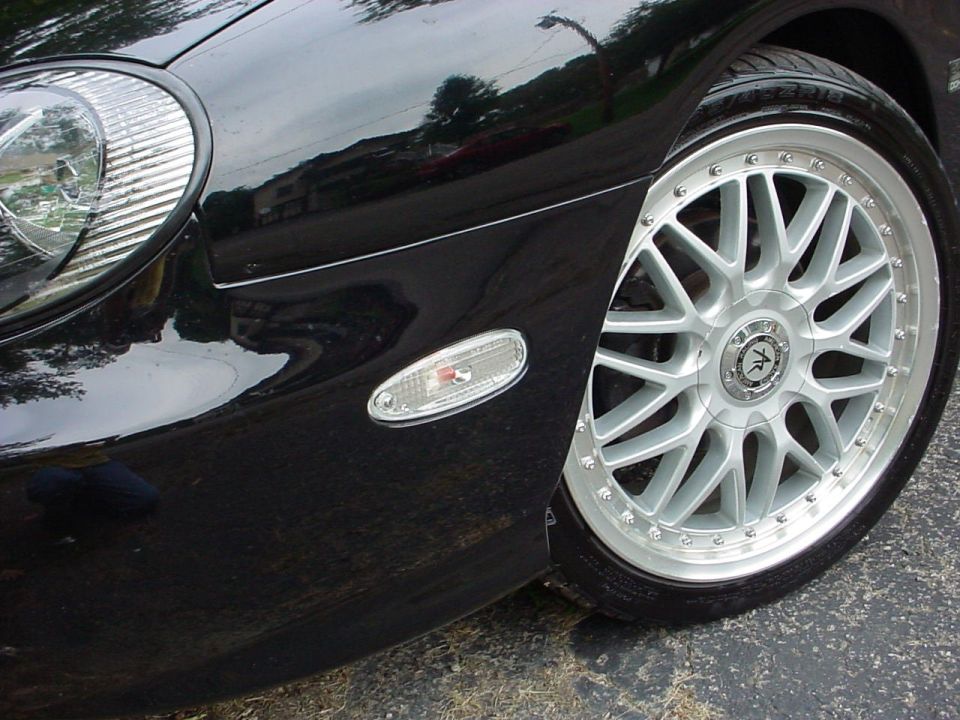 Silver mesh-spoke aftermarket wheel with polished riveted lip on black sedan