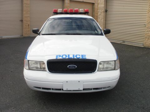 2002 Ford Crown Victoria - This police car, identified as a 2002 Ford Crown Victoria, is parked in front of garage doors.