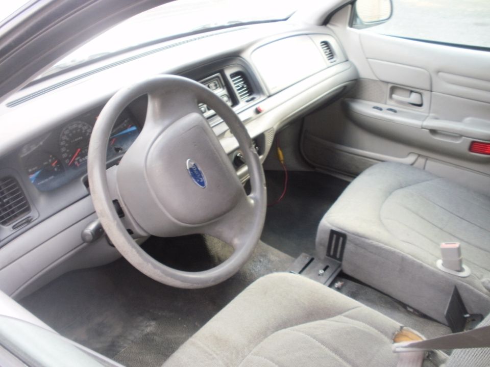 Gray interior of a 2002 Ford Crown Victoria, showing the steering wheel, dashboard, and passenger seat