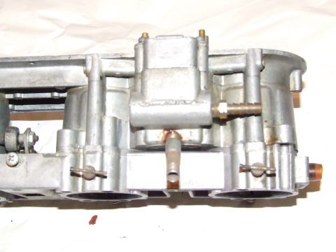 1973 Ford Mustang - This is a close-up view of a carburetor assembly, showing its intricate metal components and attached fuel lines.