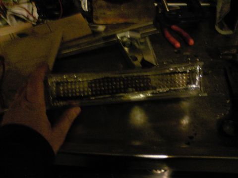 1989 Ford Bronco - A person is holding a vehicle tail light assembly over a workbench.