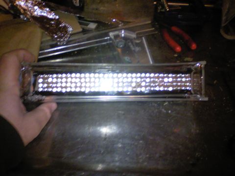 1989 Ford Bronco - A hand holds a rectangular LED light bar with numerous small, bright bulbs.