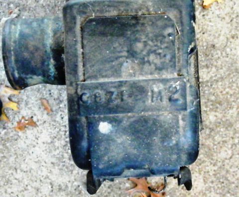 1968 Mercury Cougar - Close-up of a black automotive part with embossed text and a pipe fitting, likely a component from a vehicle.