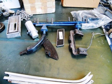 1968 Mercury Cougar - Various automotive parts, including a shifter and pedals, are displayed on a green surface, possibly for sale or restoration.