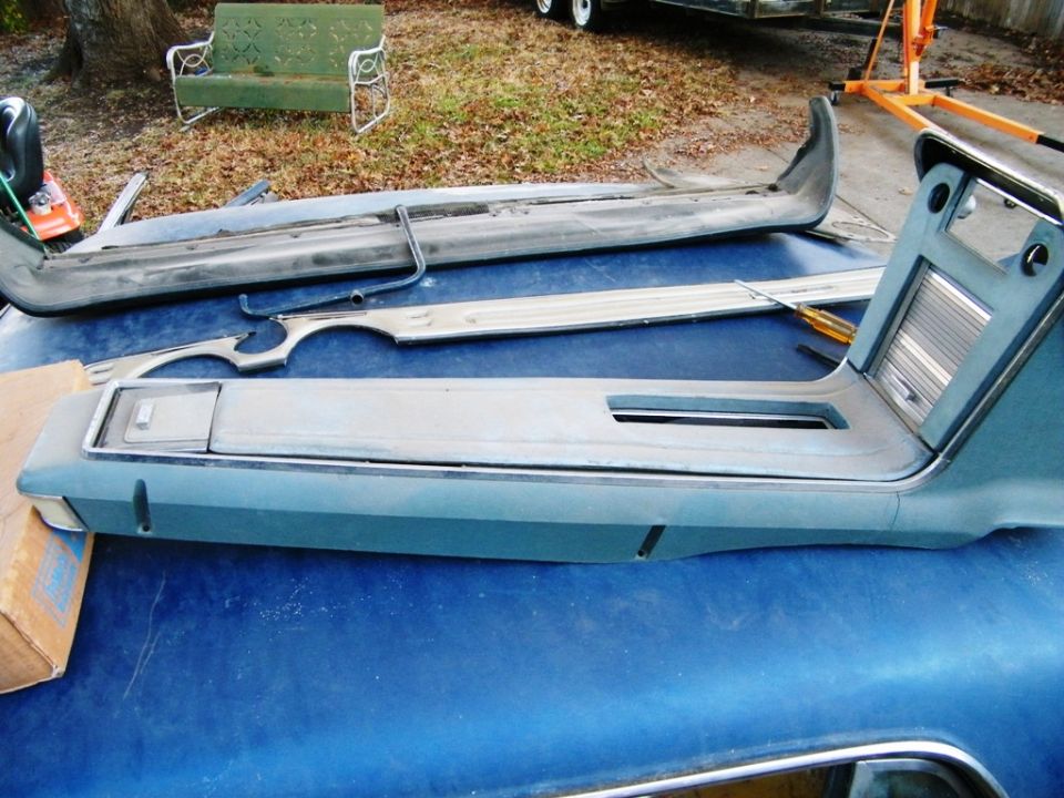 Car interior parts including a center console and dashboard trim pieces laid out on a blue surface