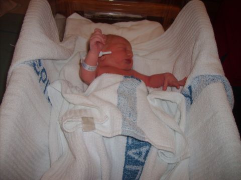 1989 Ford Bronco - A newborn baby is swaddled in white blankets, with a hospital identification bracelet on its wrist.