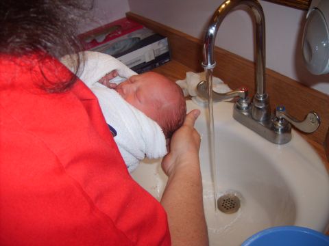 1989 Ford Bronco - A baby is being bathed in a sink with water running from the faucet.