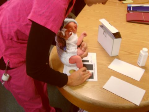 1989 Ford Bronco - A baby is held over a chart on a table, with a small white bottle and a box nearby.