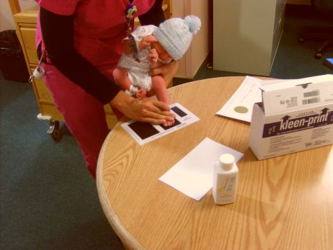 1989 Ford Bronco - A healthcare worker inks a newborn's foot for identification purposes on a wooden table.