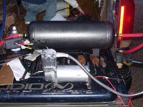 1991 Ford Bronco - An air compressor and tank are installed in the bed of a truck, connected by red hoses.