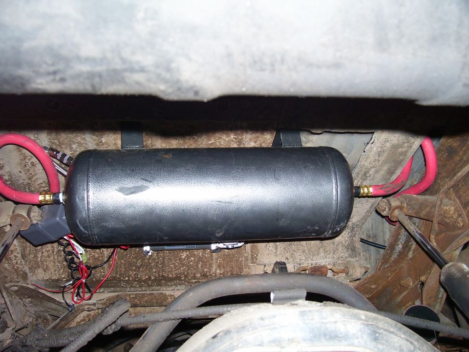 Black air tank with red hoses mounted under a vehicle