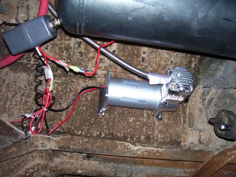 1991 Ford Bronco - Underside view of an aftermarket air compressor and tank system installed on a vehicle.