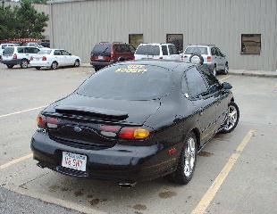 1997 Ford Taurus - A black Ford Taurus coupe is parked in a lot with other vehicles visible in the background.