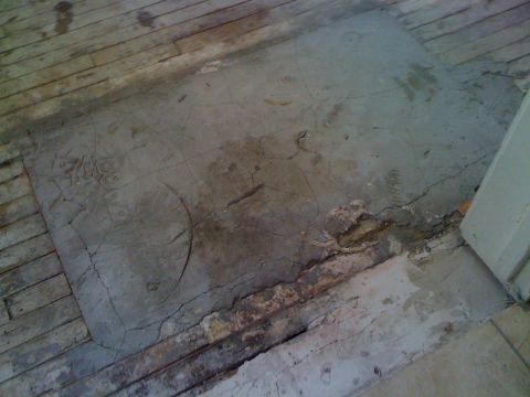 1968 Ford Mustang - A section of cracked concrete is visible on a floor made of weathered wooden planks.