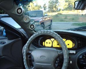 1997 Ford Taurus - Interior view of a car's dashboard and steering wheel, with a red pickup truck in the background.