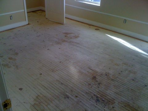 1968 Ford Mustang - Room interior with unfinished wood flooring, showing stains and light from a window.