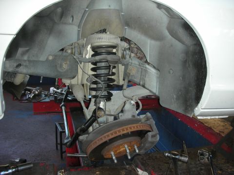 2004 Ford Crown Victoria - Close-up of a vehicle's front suspension and brake system, likely in a repair shop.