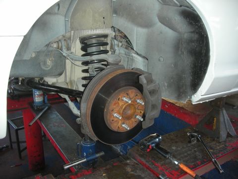 2004 Ford Crown Victoria - The vehicle's suspension and brake system are shown with various tools nearby, indicating maintenance work.
