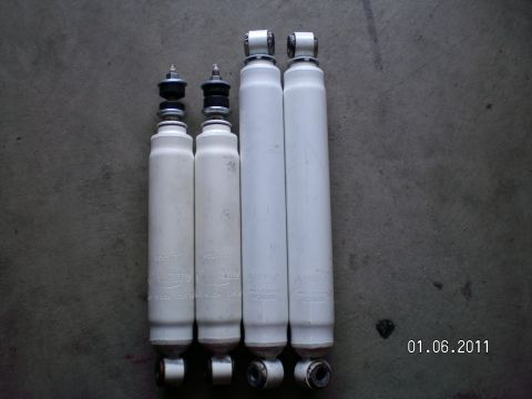 1996 Ford Bronco - Four white Rancho lift shocks are laid out on a gray surface, showing visible branding and mounting hardware.