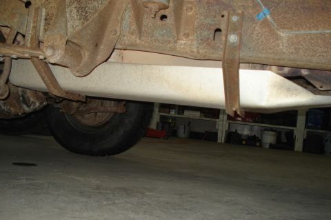 1979 Ford Bronco - The underside of a vehicle reveals a fuel tank and a tire, with visible rust on the frame.
