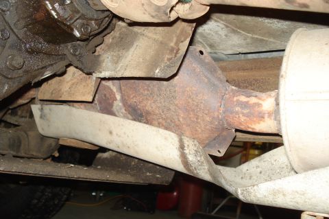 1979 Ford Bronco - The underside of a vehicle shows a rusty catalytic converter and exhaust system components.