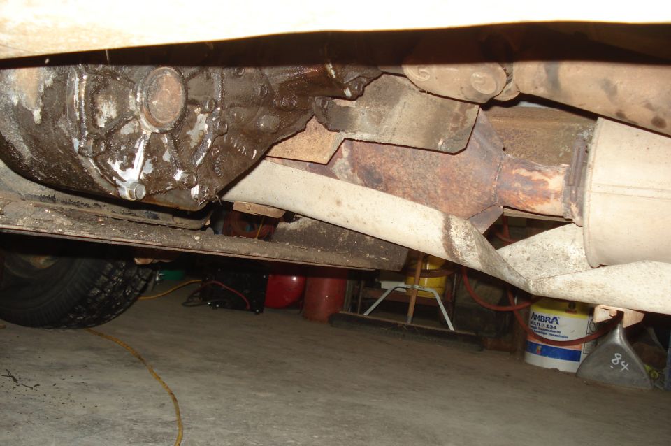 Underside view of a vehicle's drivetrain and exhaust system, showing a transfer case and muffler