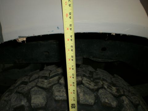 1995 Ford Bronco - Measuring tire clearance with a tape measure against the fender well.